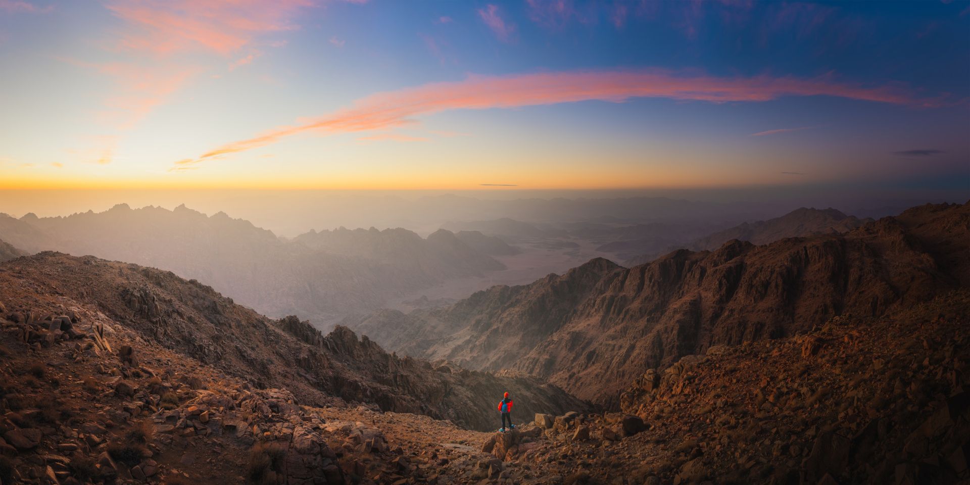NEOM, SAUDI ARABIA - DECEMBER 13 : An explorer enjoys the view at sunset from the mountains of Trojena on December 13, 2022, in NEOM, Saudi Arabia
