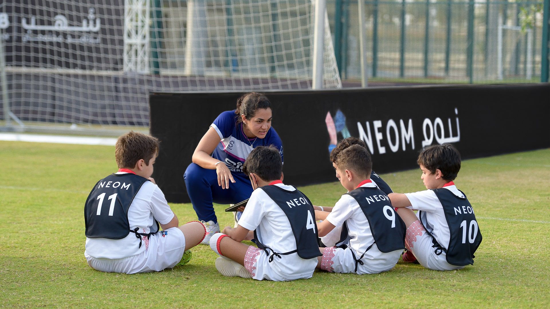 A coach instructing young athletes for a football match at the Shuhub community program